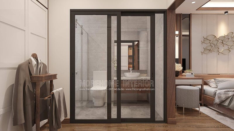 Trang trí nội thất phòng ngủ khép kín với xu hướng mở khi sử dụng tấm ốp tường gỗ óc chó như tạo ranh giới phân chia cùng thiết kế cửa kính trượt. Thiết kế nội thất